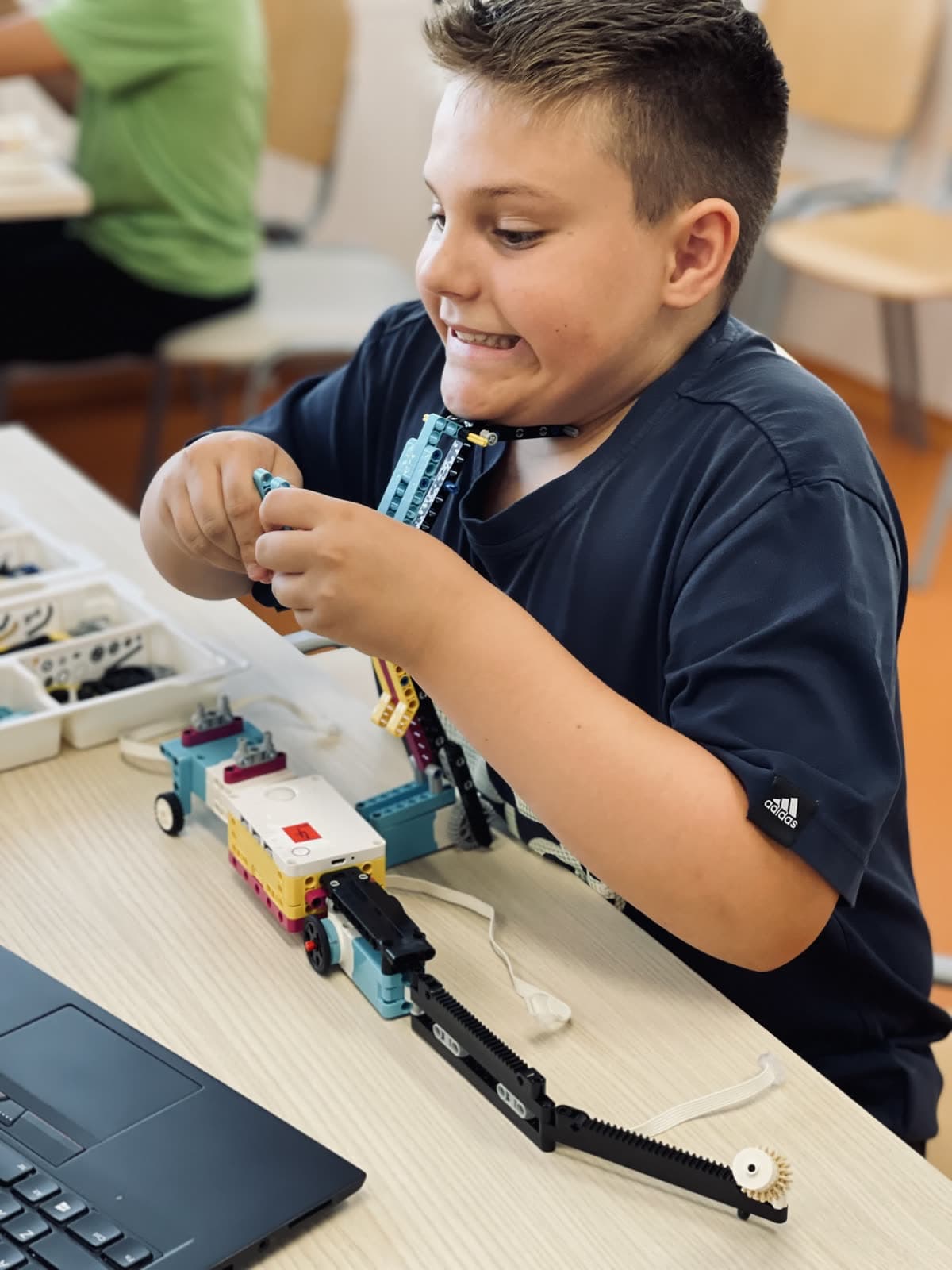Otrok sestavlja mehanizem LEGO robota na tečaju